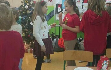 Uczniowie klasy trzeciej dzielący się opłatkiem