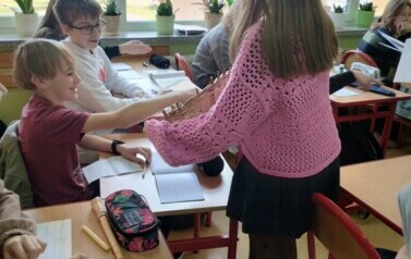 Uczennica rozdająca lizaki w klasie sz&oacute;stej