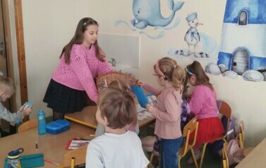 Uczennica klasy 4 rozdająca lizaki w oddziale przedszkolnym