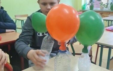 Uczeń obserwuje doświadczenie samopompujące się balony