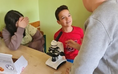 Uczniowie pracują przy użyciu mikroskopu optycznego