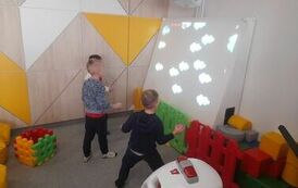 trzech chłopc&oacute;w gra na interaktywnej tablicy