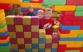 trzech chłopc&oacute;w buduje  tamę z dużych klock&oacute;w