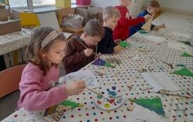 przedszkolaki wykonują choinki z drewna